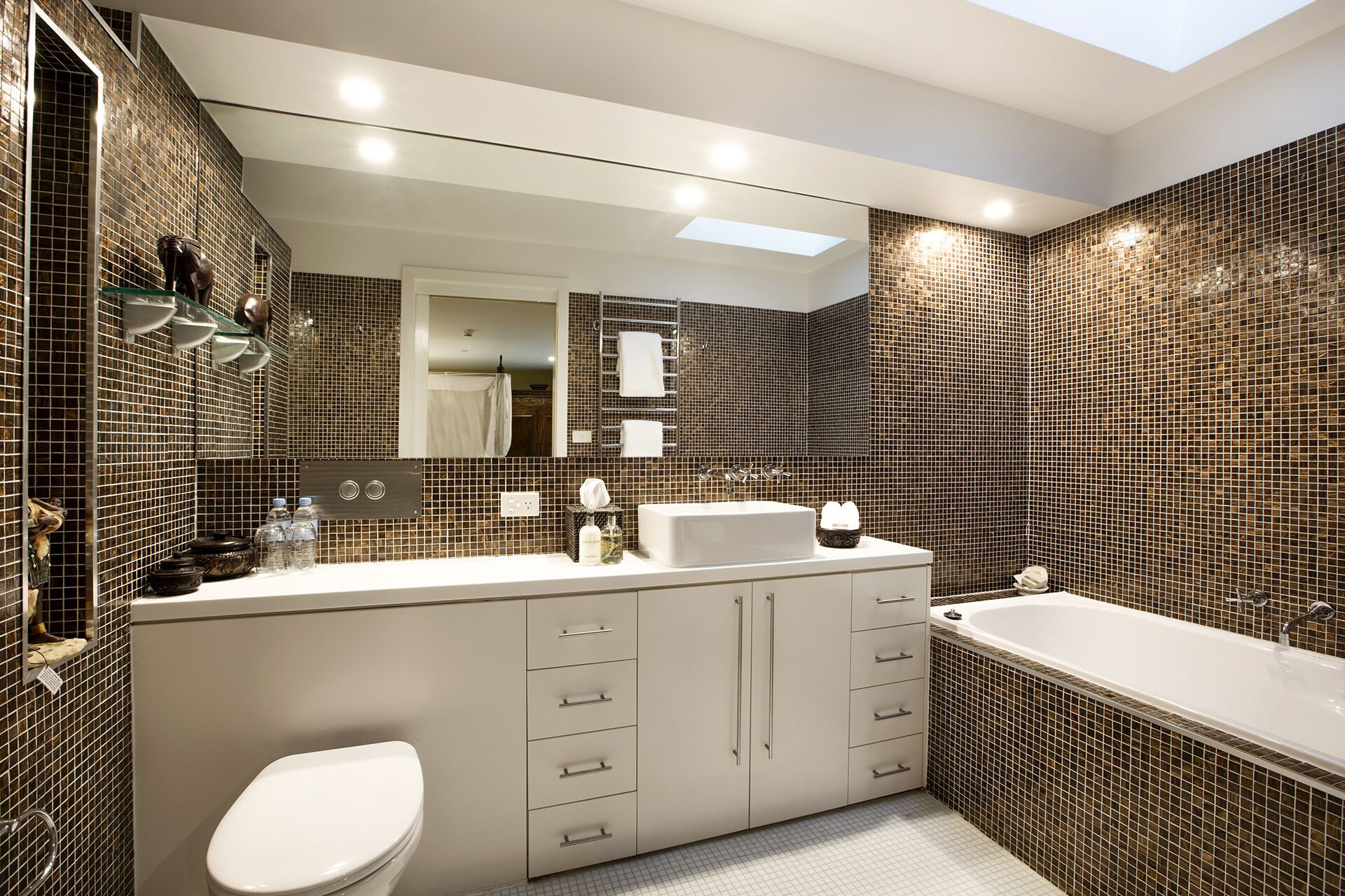 Une salle de bain moderne avec un grand miroir, une baignoire et des toilettes.