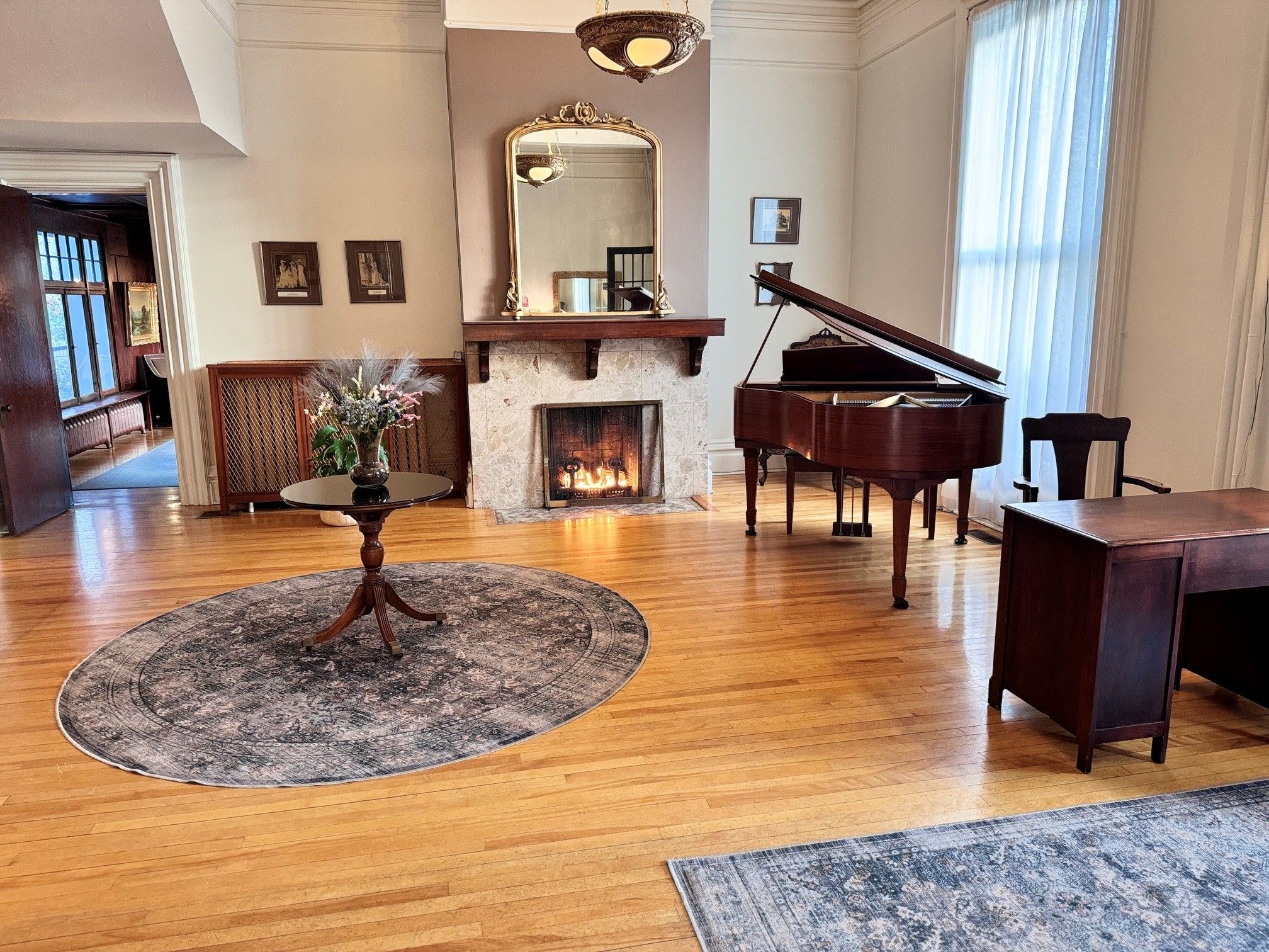 A spacious living room with a grand piano, a fireplace, and a large mirror.