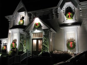 A house with a front porch, a Christmas tree, and holiday wreaths. - Shadow Lawn Inn (Rothesay)