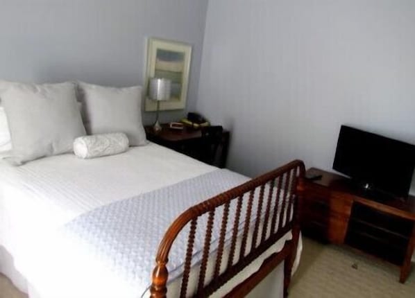 A hotel room with a bed, a wooden headboard, a television, and a nightstand. - Shadow Lawn Inn (Rothesay)