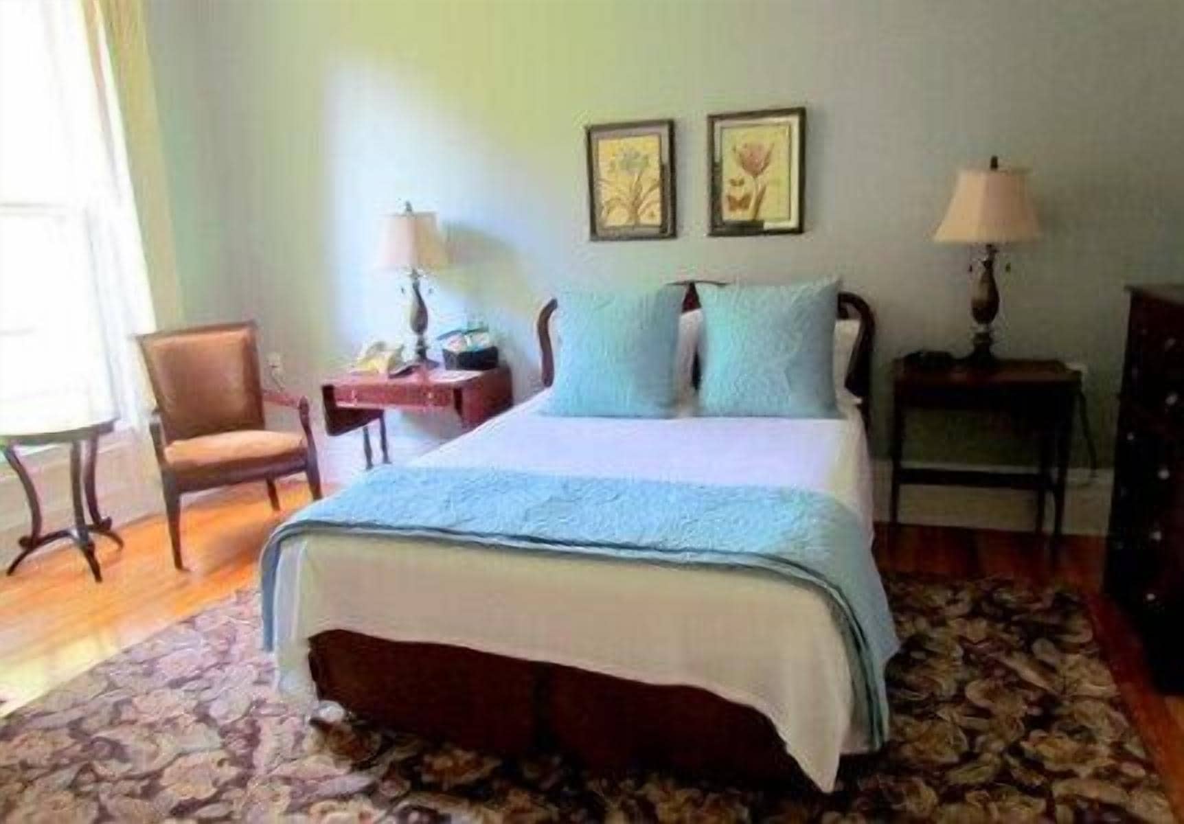A bedroom with a bed, two bedside tables, a chair, and a rug.
