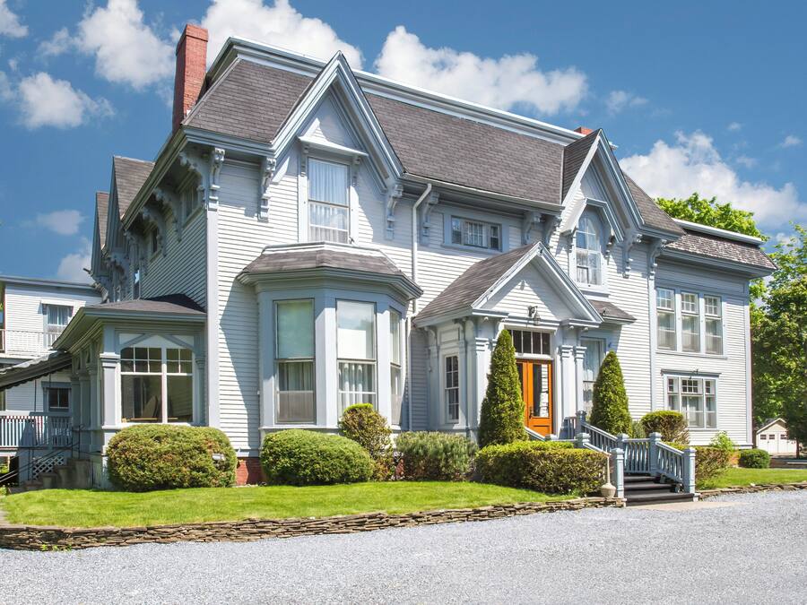 A large, two-story house with a prominent front porch, a chimney, and a well-maintained lawn.