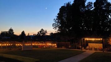 Un patio al aire libre con luces colgantes, una pérgola y una zona de estar.