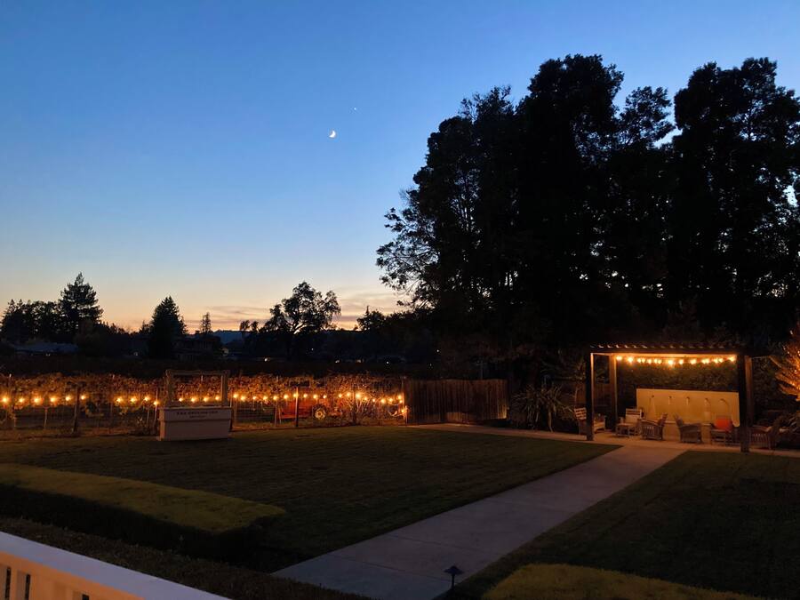Un patio al aire libre con luces colgantes, una pérgola y una zona de estar.