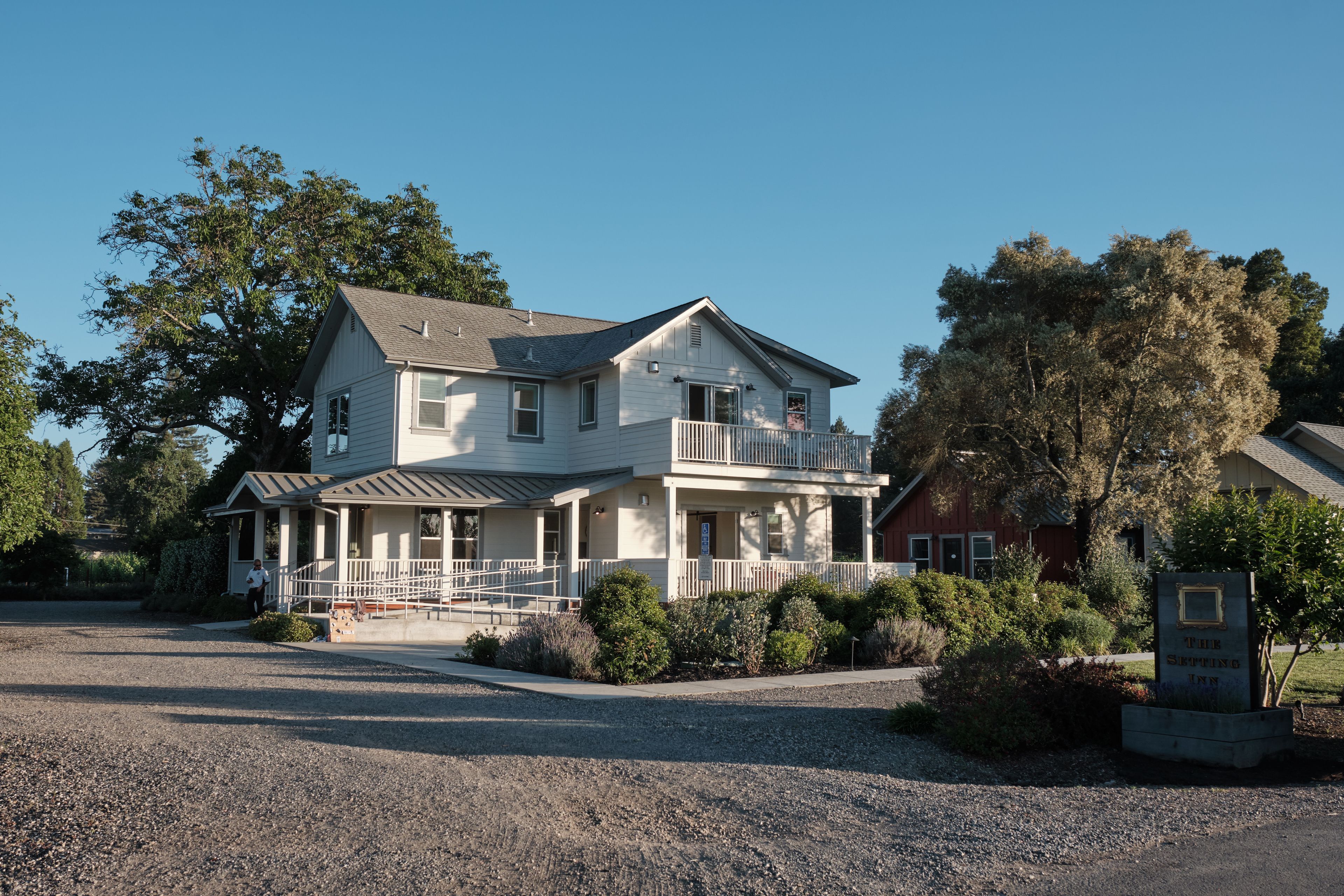 A two-story house with a porch, a small balcony, and a gravel driveway.