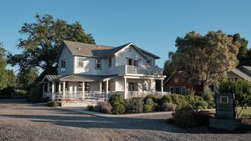 A two-story house with a porch, a small balcony, and a gravel driveway.