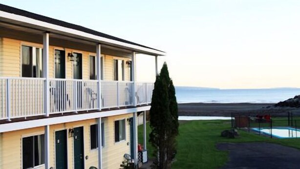Een gebouw met twee verdiepingen, een balkon, een zwembad en uitzicht op de oceaan.