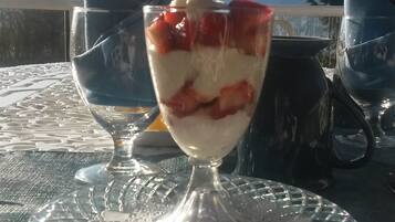 Dessert i et glas på et bord med udsigt til bjerge i baggrunden.