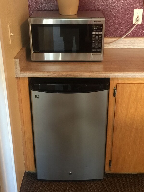 Una cocina compacta con un microondas de acero inoxidable sobre un lavavajillas empotrado.