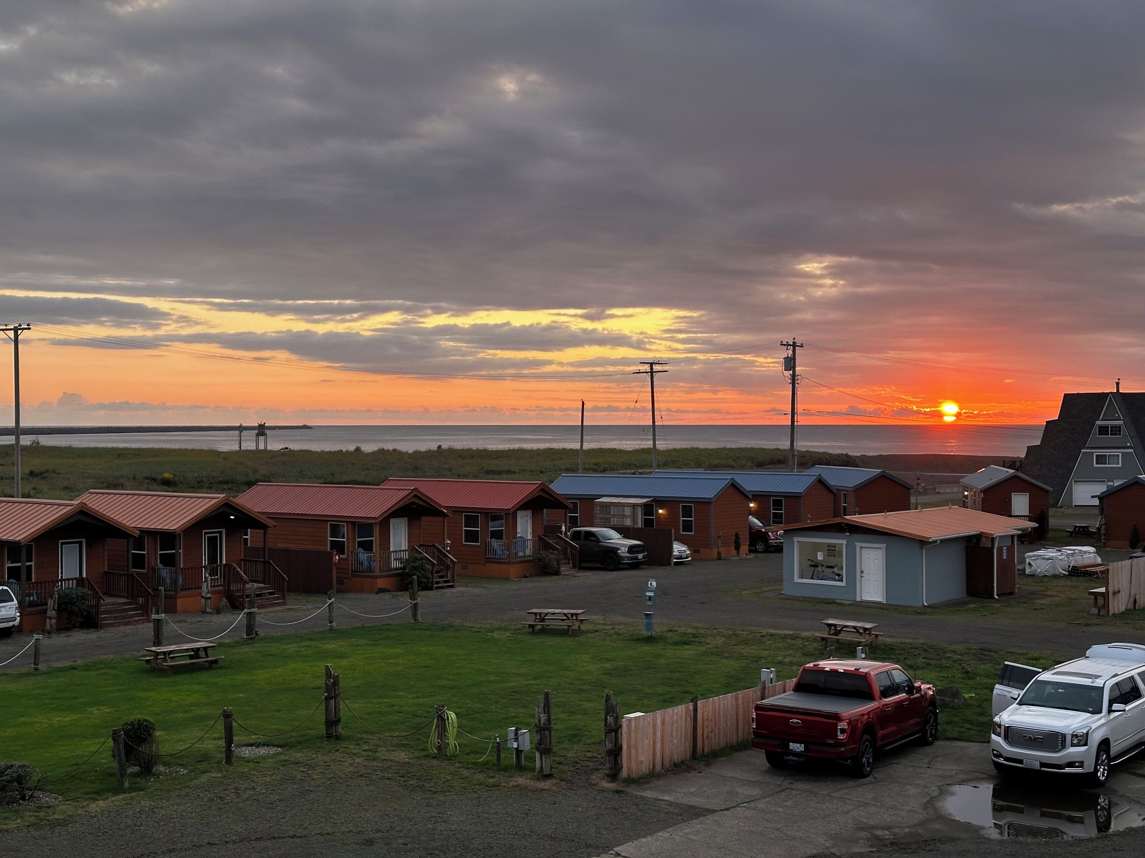 A row of wooden cabins with a sunset in the background.
