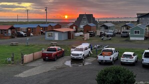 A campground with RVs and cars parked, cabins with small porches, and a sunset over the water. - Westport Inn (Westport)