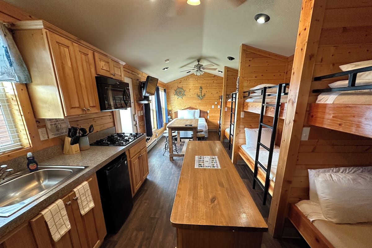 Quarto estilo cabana com beliches, cozinha compacta e área de refeições.