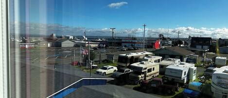 A parking lot with RVs and cars, a building with a red sign, and a clear blue sky.