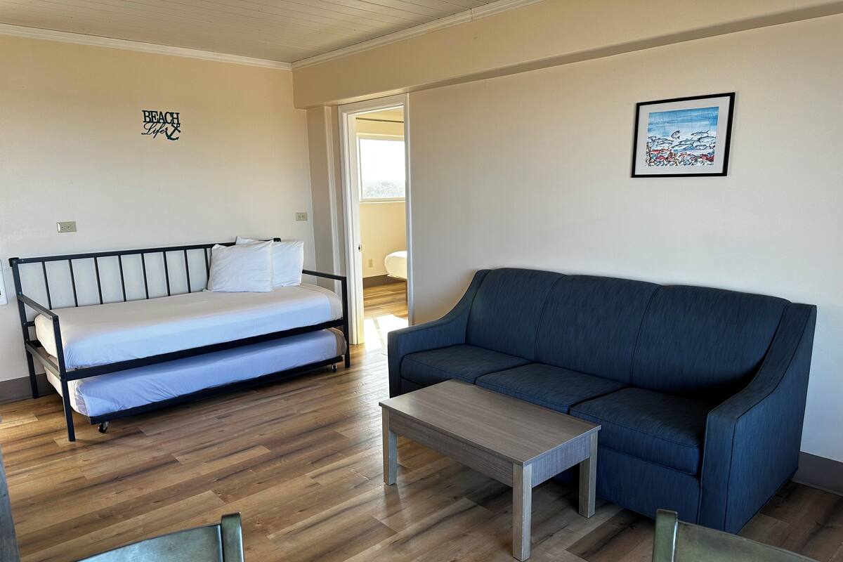 Um quarto com cama, sofá, mesinha e cadeira.