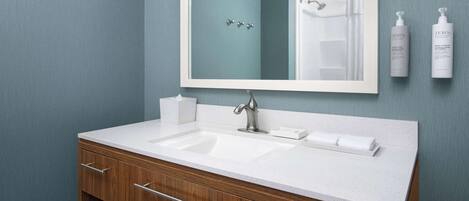 A bathroom with a white sink, wooden vanity, and a large mirror.