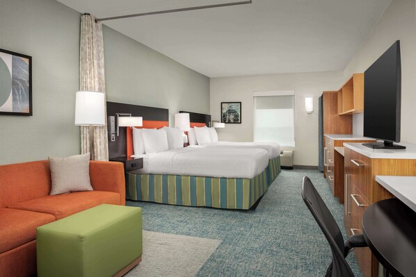 A hotel room with a bed, a sofa, a desk, and a television. - Home2 Suites by Hilton Austin Round Rock (Round Rock)
