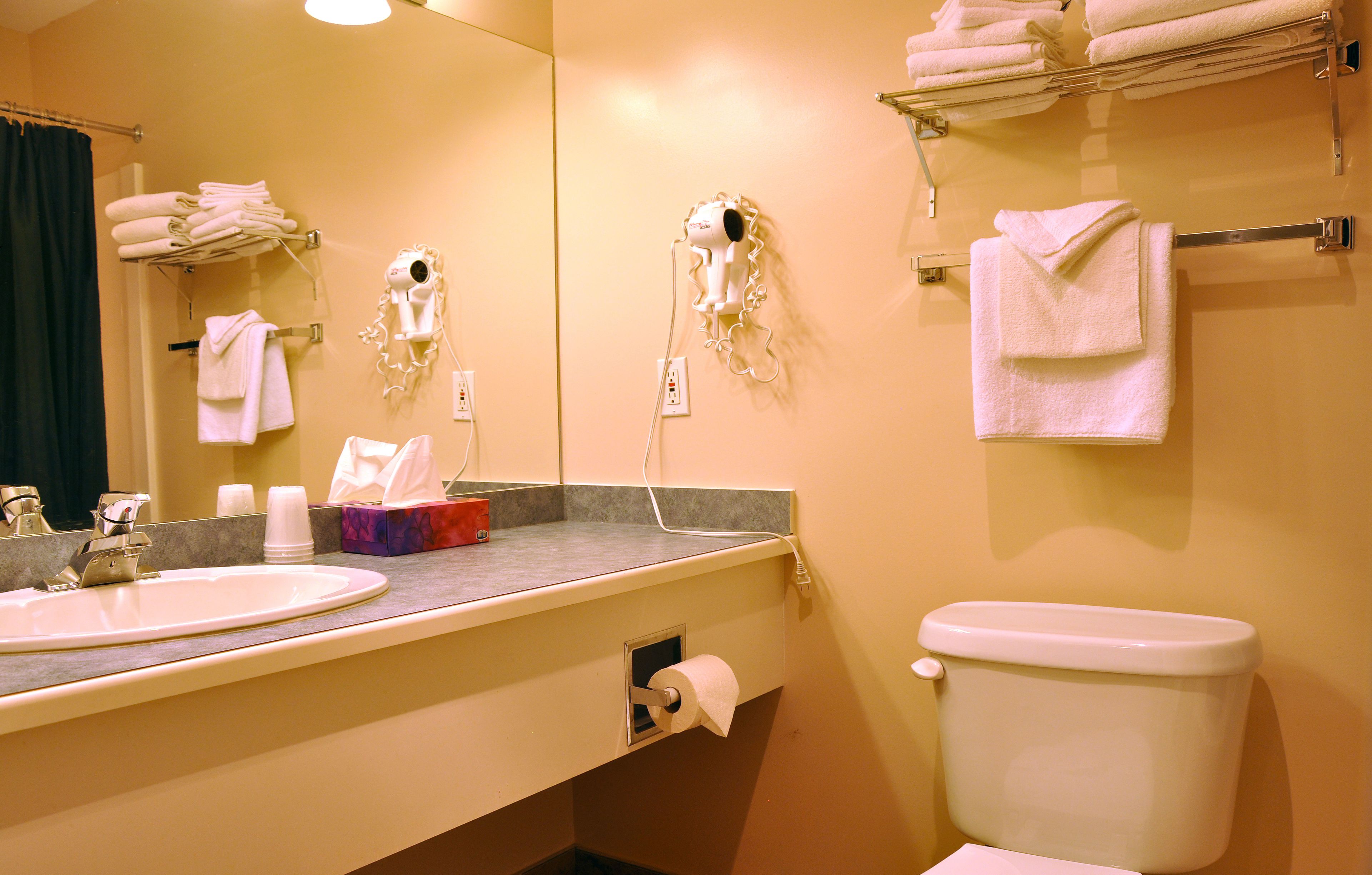 Un baño con lavamanos, espejo, toallero y retrete.