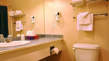 Un baño con lavamanos, espejo, toallero y retrete.