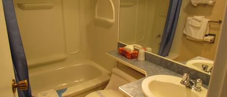 A bathroom with a bathtub, toilet, sink, and a mirror.