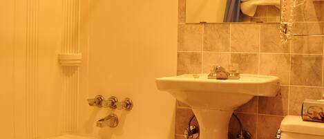A bathroom with a bathtub, a sink, a toilet, and a mirror.