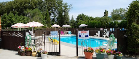 Una piscina al aire libre de temporada, sombrillas