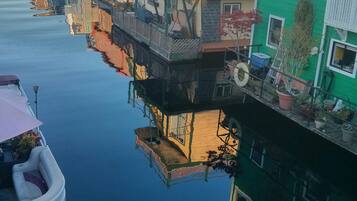 A row of floating houses with balconies, connected by walkways, and a boat docked nearby.