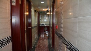 A marble hallway with patterned tiles, wooden doors, and a microwave in the distance. - Everest Hostel (Kowloon)