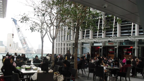 An outdoor dining area with tables and chairs, surrounded by buildings and a view of a bridge. - Everest Hostel (Kowloon)