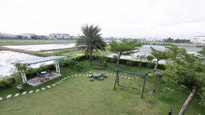 A grassy outdoor area with a gazebo, palm tree, and a swing set.