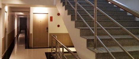 A modern hotel interior with a staircase, a hallway, and a door.