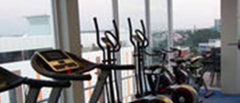 Une salle de sport équipée d’appareils de cardio, notamment des tapis de course et des machines elliptiques, de grandes fenêtres et une vue sur la ville.