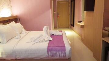 A hotel room with a neatly made bed, a bedside table with a lamp, and a door leading to another room.