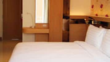 Habitació d'hotel amb un llit gran, un panell de fusta al capçal, una tauleta de nit i un mirall.