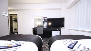 Habitación de hotel con dos camas, un escritorio, televisor de pantalla plana, cafetera y espejo.