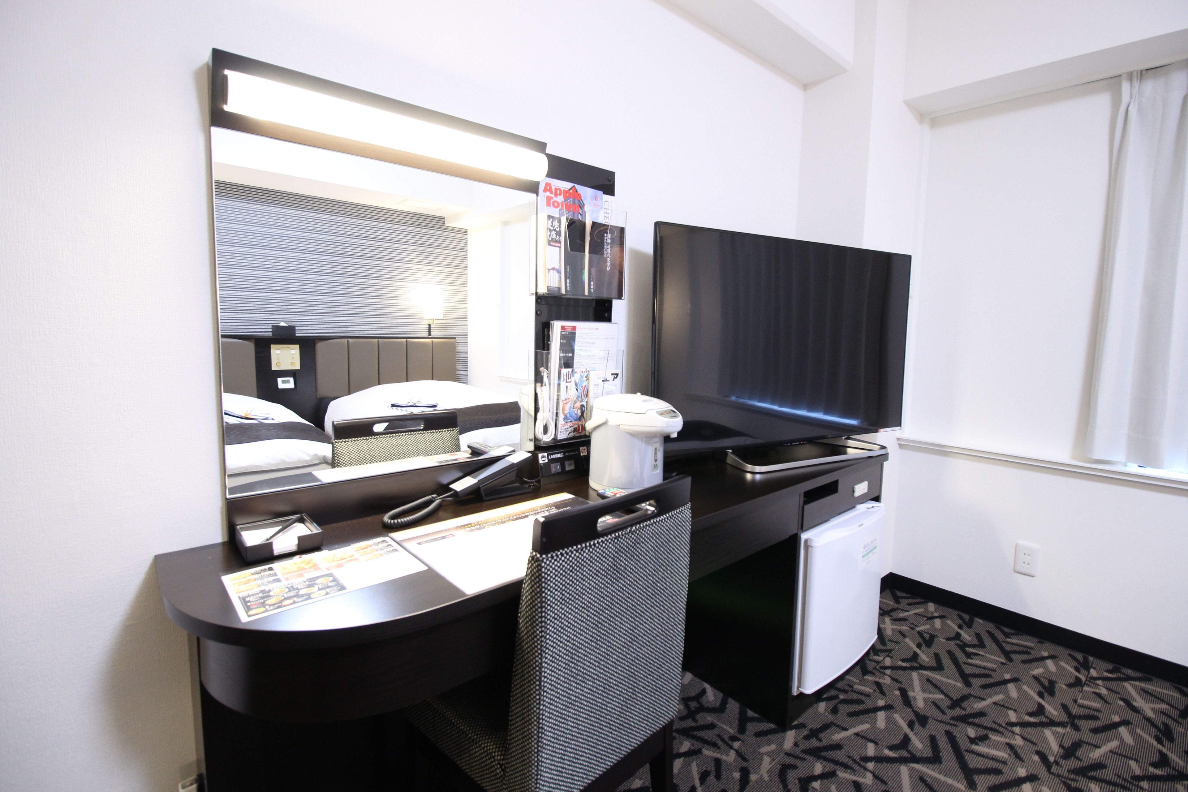Une chambre d’hôtel équipée d’un bureau, d’une chaise, d’une télévision, d’un mini-réfrigérateur et d’un four à micro-ondes.