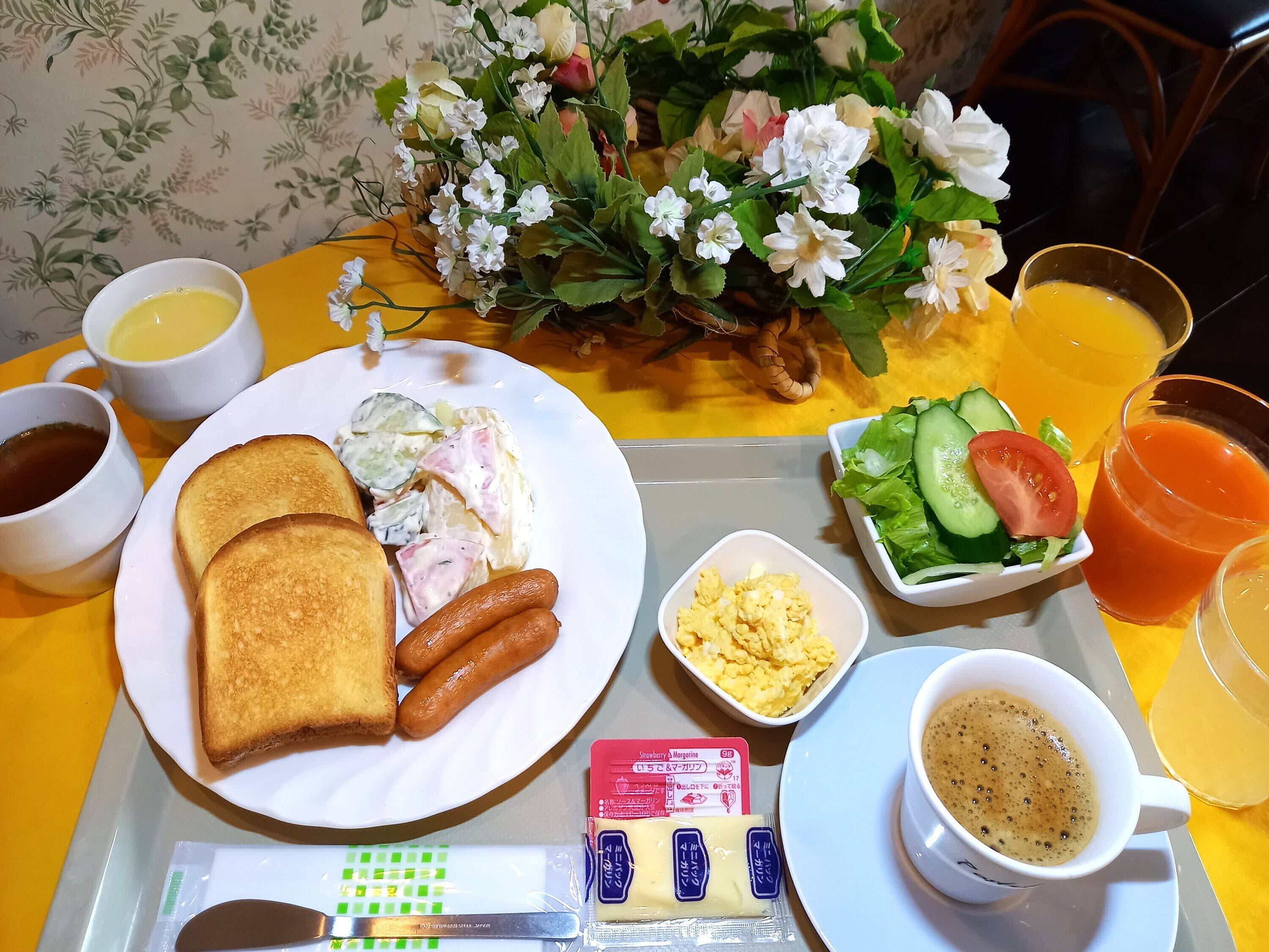 A breakfast tray with toast, sausages, scrambled eggs, a salad, and coffee.