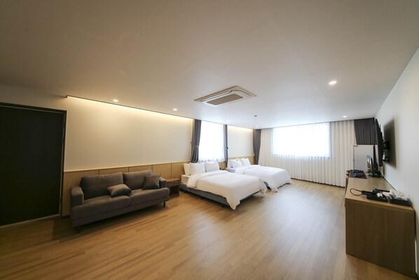 Una habitación de hotel moderna con una cama grande, un sofá, un escritorio y un televisor.