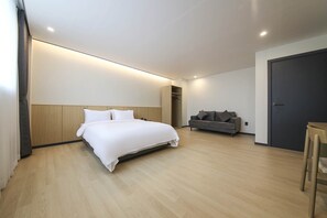 Una habitación de hotel moderna con una cama grande, un sofá, un armario y una puerta.