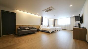 Una habitación de hotel moderna con sofá, dos camas, escritorio y televisor.