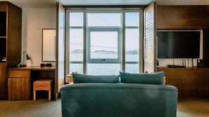 Un dormitorio con una cama grande, un escritorio, una silla, un televisor y vista al agua.