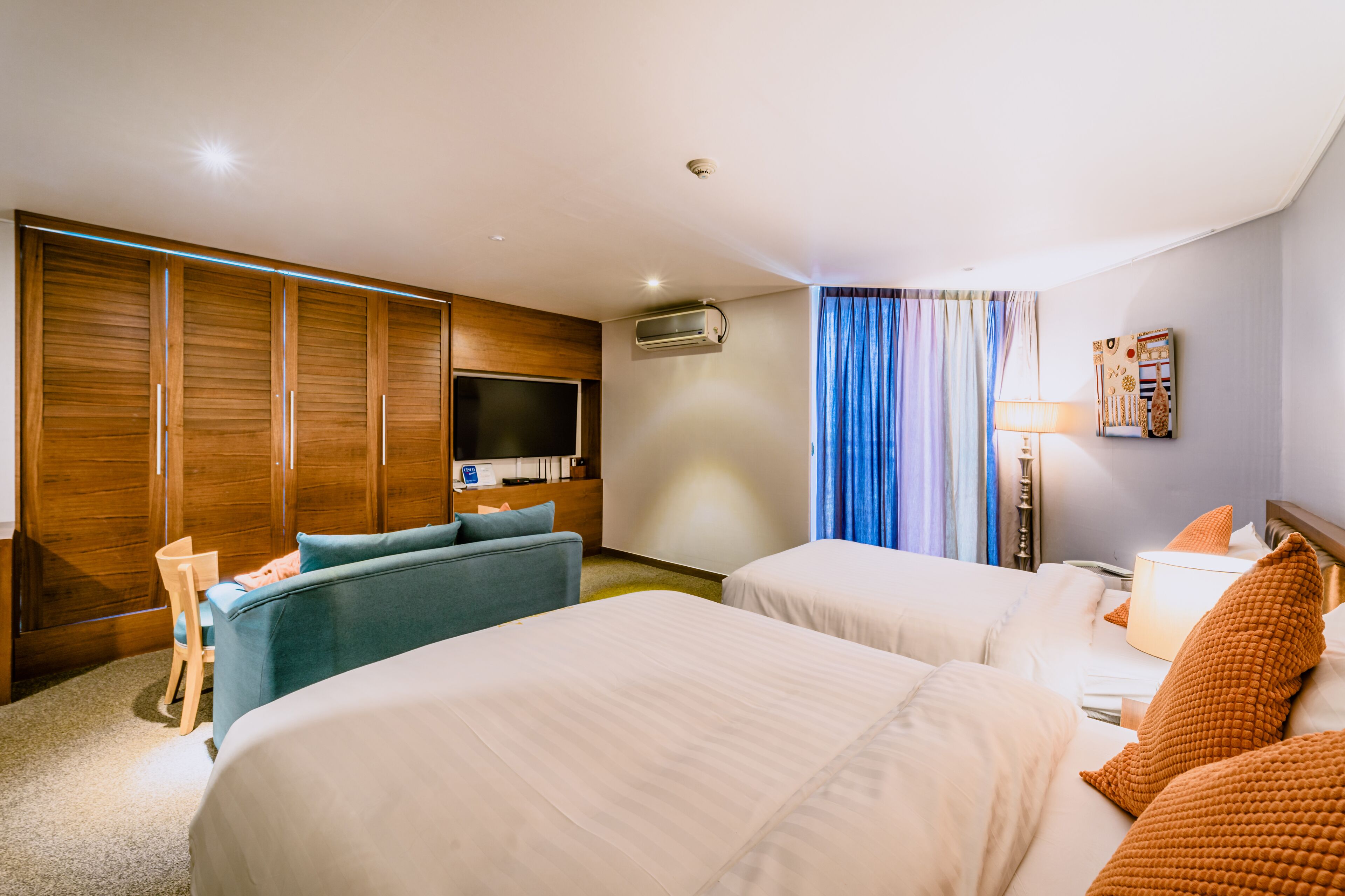 A hotel room with two beds, a TV, a desk, and a wardrobe.