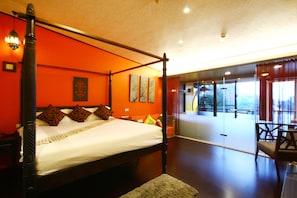 A four-poster bed with a white bedspread and brown pillows, a wooden floor, and a view of a balcony with a chair. - Mystery 13 B&B (Luodong)