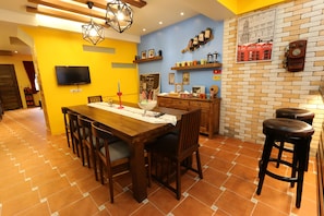 A dining area with a wooden table, chairs, and a TV mounted on the wall. - Mystery 13 B&B (Luodong)