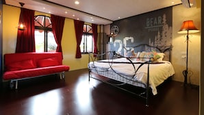 Une chambre à coucher avec un lit, un canapé rouge, une fresque murale et une lampe.