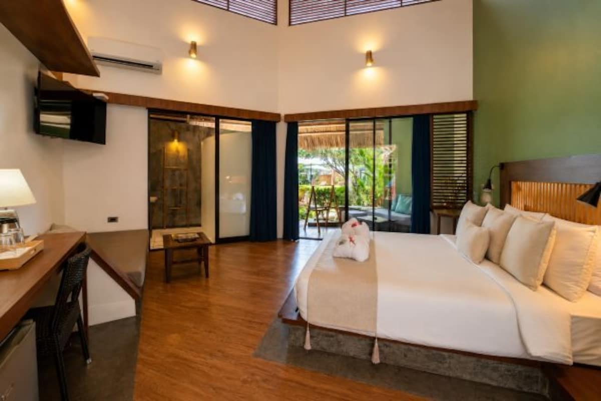 A hotel room with a bed, desk, and a sliding glass door leading to a balcony.
