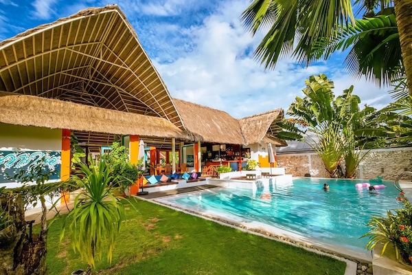 Una piscina al aire libre, sombrillas, sillones reclinables de piscina