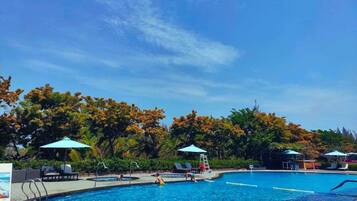 Una piscina al aire libre, sombrillas, sillones reclinables de piscina