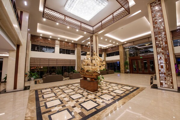Eine geräumige Lobby mit einem großen Schiffsmodell, bequemen Sitzgelegenheiten und einem gemusterten Boden.
