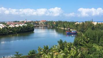 A river with a bridge, surrounded by lush greenery and palm trees.