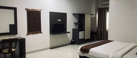 A hotel room with a bed, a desk, a TV, a wardrobe, and a mirror.